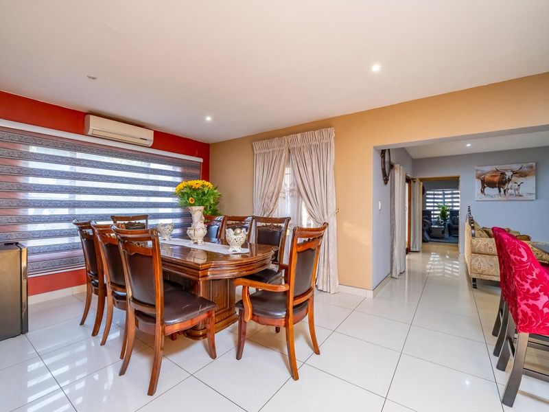 Spacious dining area featuring tiled flooring, recessed lighting, and a wall-mounted air conditioning unit, providing a comfortable space for family meals and entertaining.