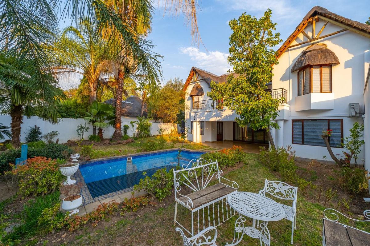 Rear view of the townhouse featuring a private swimming pool, landscaped garden, and a balcony overlooking the outdoor entertainment area.