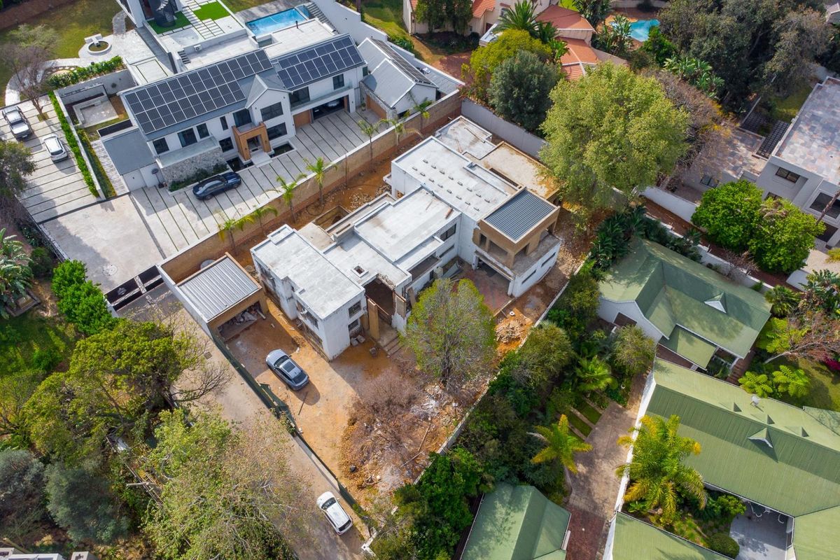 Aerial view of a residential property currently under construction, featuring a large building footprint, flat roof structure, and surrounding garden area.