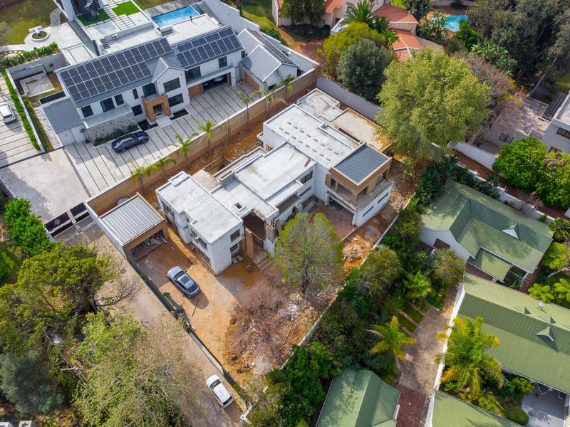 Aerial view of a residential property currently under construction, featuring a large building footprint, flat roof structure, and surrounding garden area.