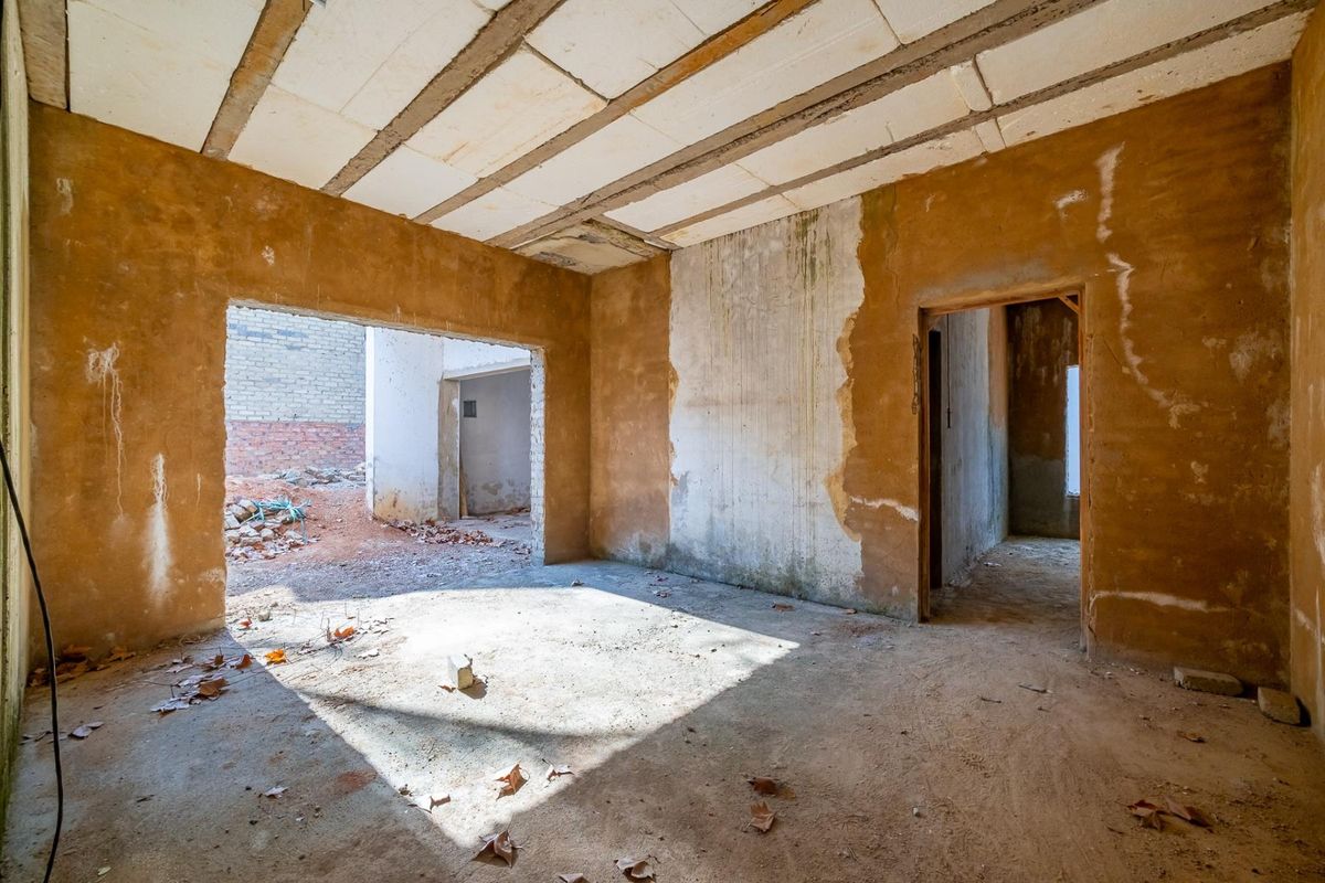 An unfinished interior space featuring exposed concrete ceiling beams and raw wall surfaces, offering a blank canvas for complete renovation and custom design.