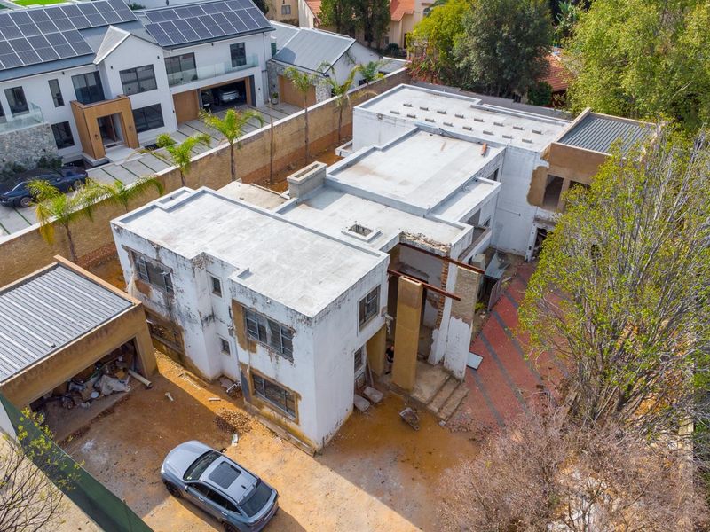 Aerial view of a residential property currently under construction, featuring a flat-roofed structure, detached garage, and paved driveway area.
