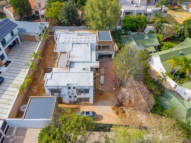 Aerial view of a residential property currently under construction, featuring a flat roof design, solar panels, and an expansive unlandscaped yard area.