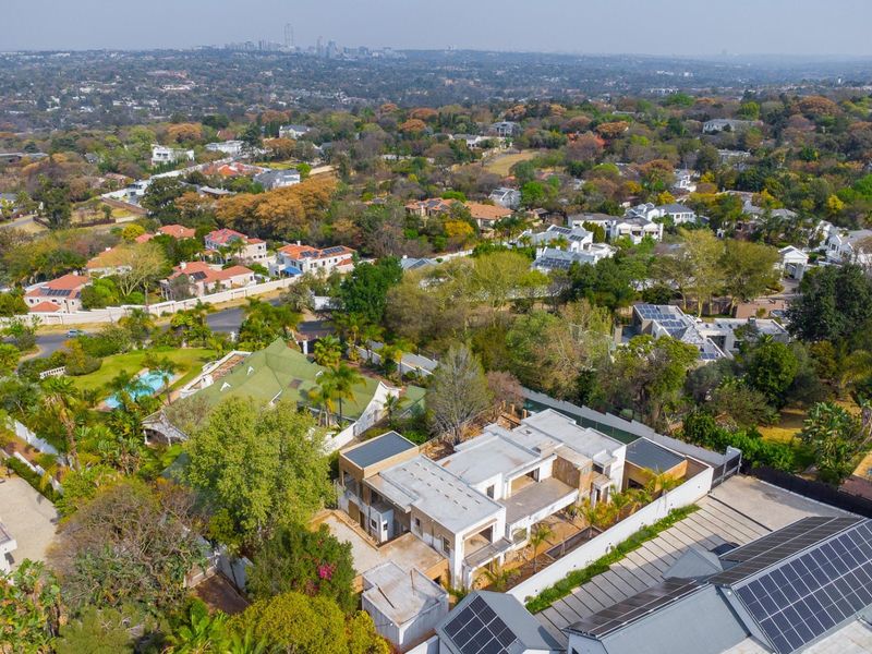 Aerial view of a residential property featuring a large dwelling, swimming pool, and solar panel installations within a leafy suburban neighborhood.