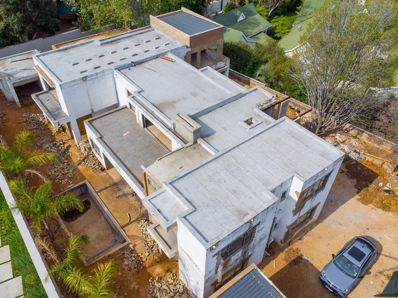 Aerial view of a residential property currently under construction, featuring a flat roof design and an unfinished swimming pool shell.