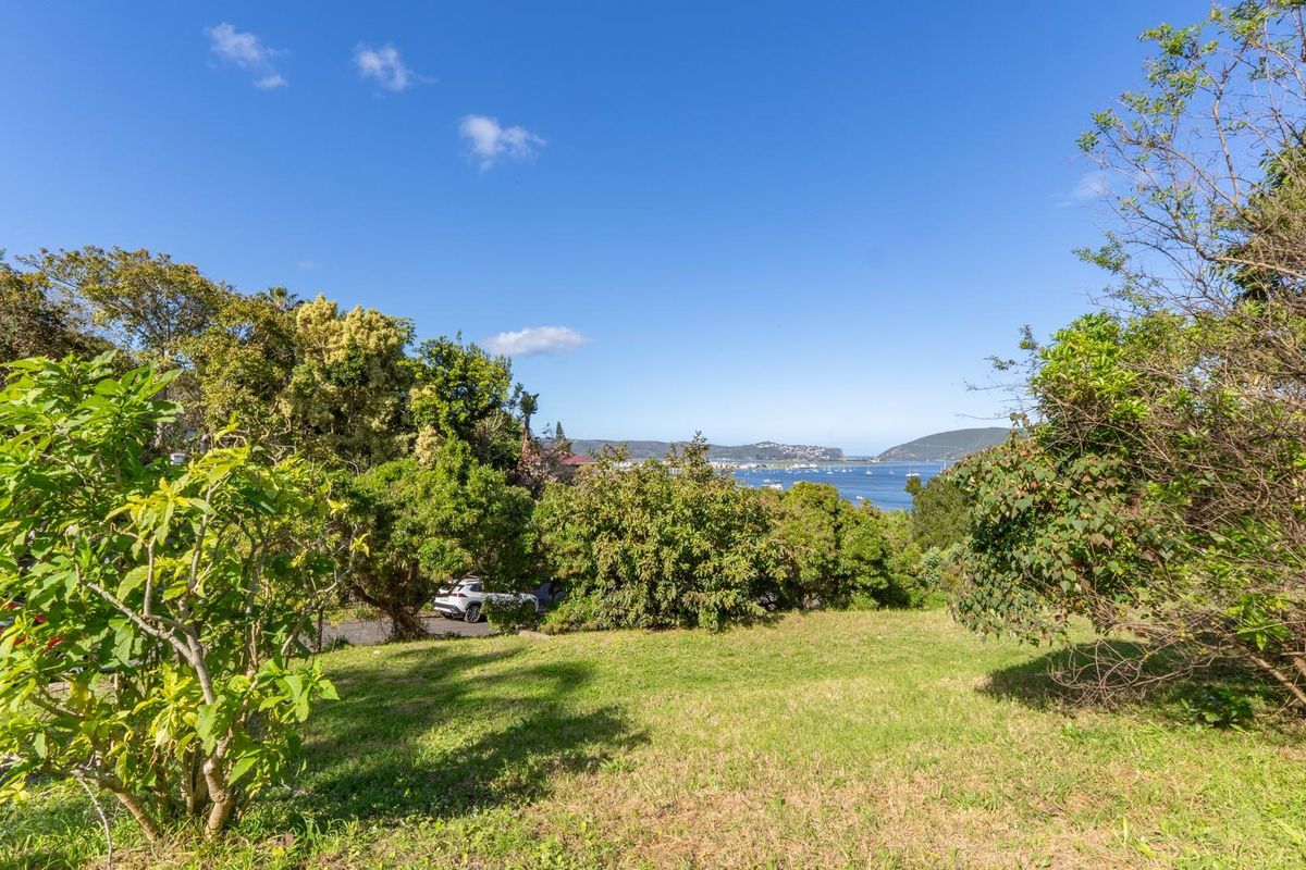 A scenic view of the coastal landscape and water, framed by established trees and greenery on the residential land.