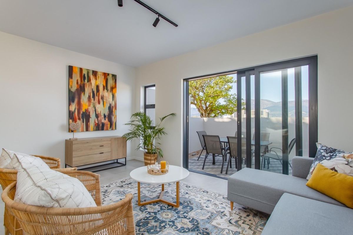 Bright living room featuring modern track lighting, tiled floors, and large sliding glass doors that open onto a private patio area.