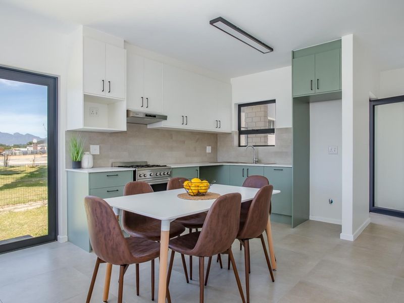Modern open-plan kitchen and dining area featuring two-tone cabinetry, gas stove, tiled backsplash, and direct access to the outdoor garden area.
