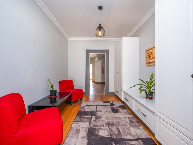 A bright entrance hall featuring polished hardwood flooring, crown molding, and extensive built-in cabinetry for storage.