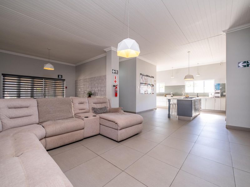Spacious open-plan living area featuring a modern kitchen with a central island, tiled flooring, and neutral finishes throughout.
