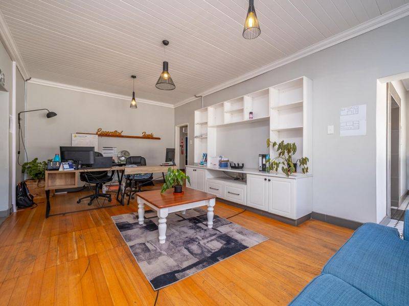A functional home office featuring polished timber flooring, a tongue and groove ceiling, and extensive built-in cabinetry for storage.