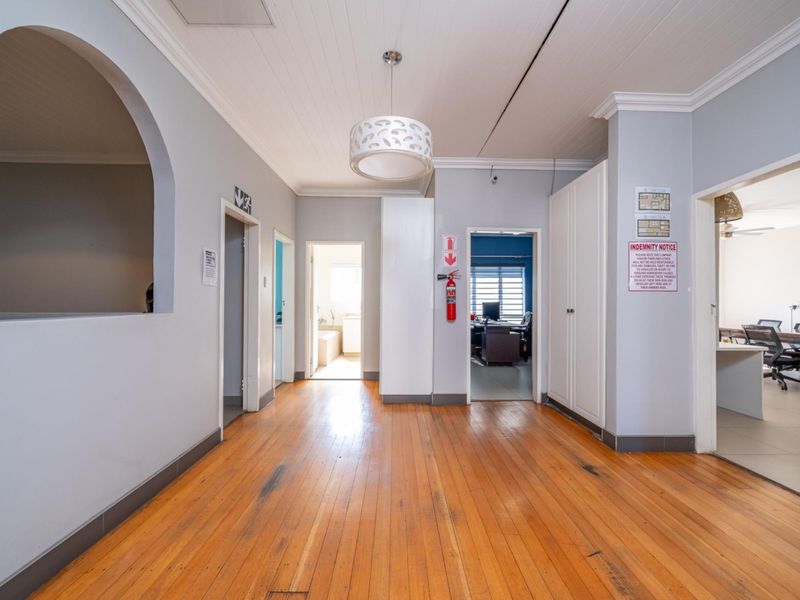 Spacious hallway featuring polished timber flooring, built-in storage cupboards, and a decorative archway leading to multiple rooms.