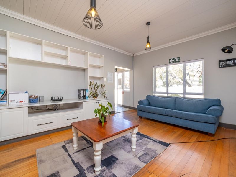 A bright living room featuring polished timber flooring, tongue and groove ceiling, and extensive built-in cabinetry for storage.