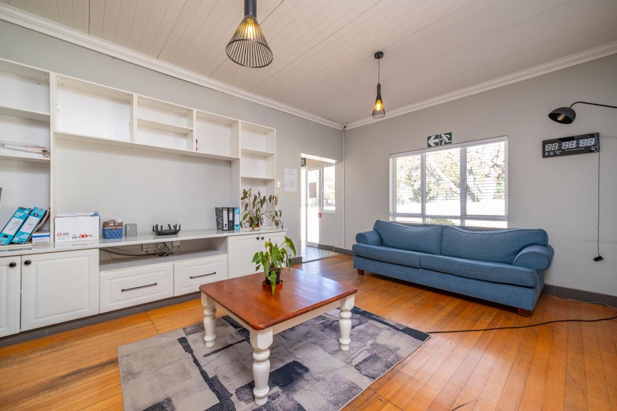 A bright living room featuring polished timber flooring, tongue and groove ceiling, and extensive built-in cabinetry for storage.