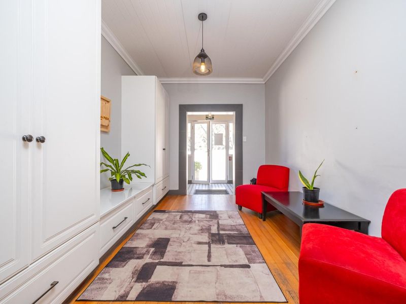 A bright and welcoming entrance hall featuring polished hardwood flooring, built-in storage cabinetry, and a classic tongue and groove ceiling.