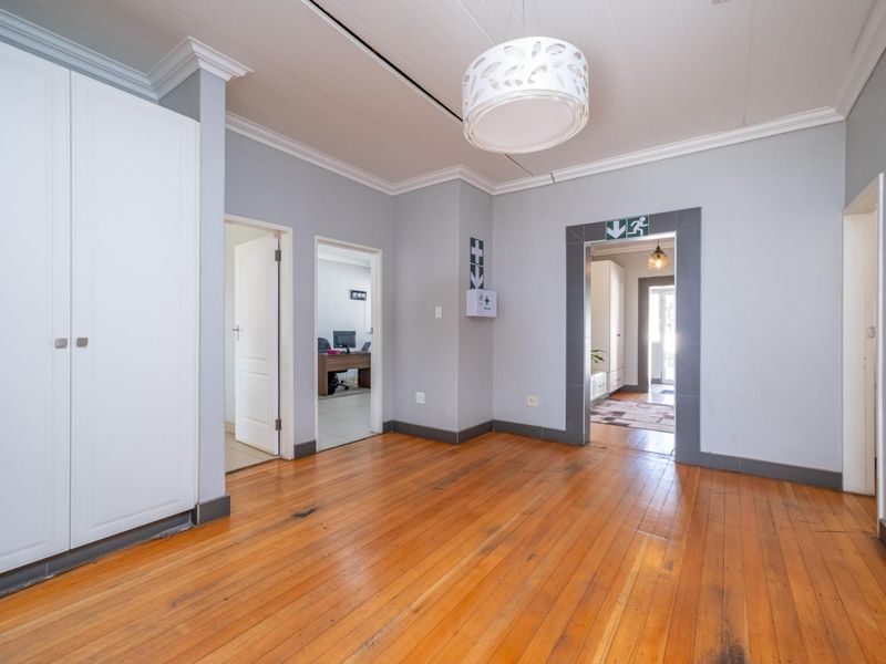 A spacious, empty hallway featuring polished timber flooring, crown molding, and a built-in cupboard, providing access to multiple rooms.