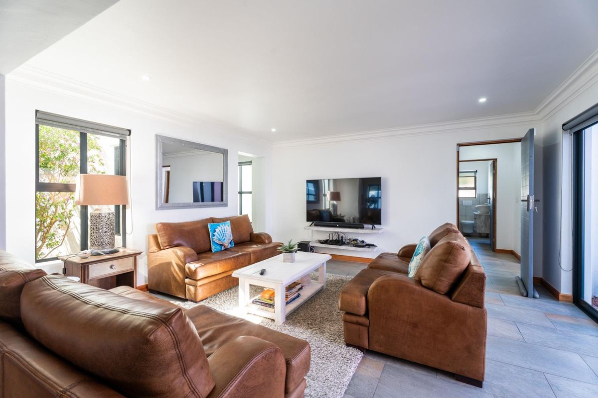 A bright and well-maintained living room featuring tiled flooring, recessed downlights, and a built-in wall shelf for media equipment.