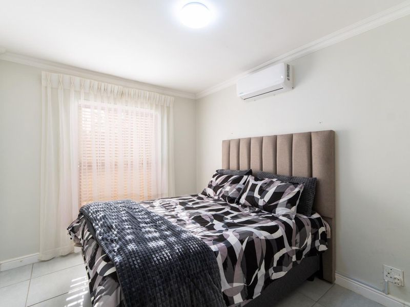 A well-maintained bedroom featuring tiled flooring, crown molding, and a wall-mounted air conditioning unit.