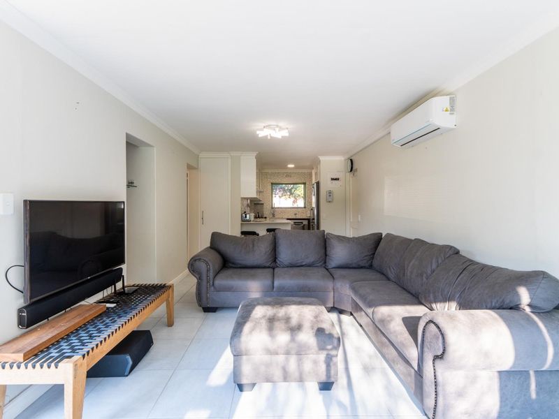 Open plan living area featuring tiled flooring and a wall-mounted air conditioning unit, flowing into a functional kitchen space.