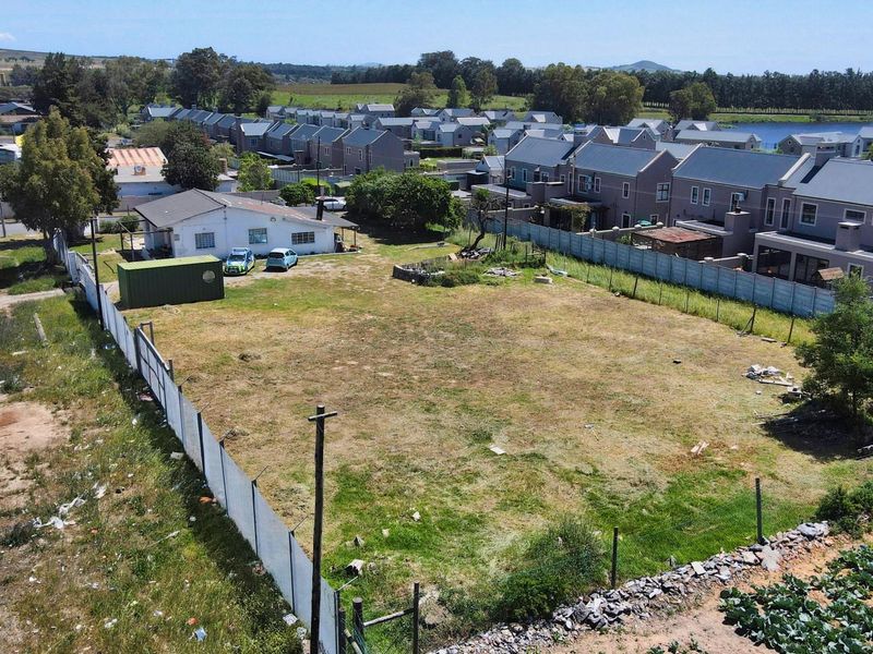 Aerial view of a vacant commercial land plot featuring perimeter fencing and surrounding residential development.