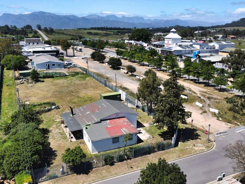 Aerial view of a commercial vacant land plot featuring an existing structure with a metal roof, situated in a developed commercial area.