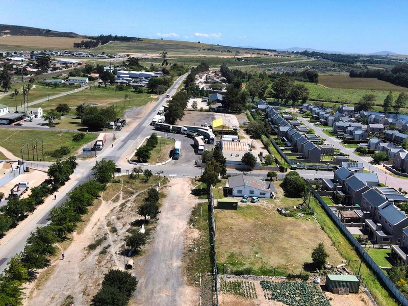Aerial view of a commercial vacant land plot situated near a main road and residential area, offering significant development potential.