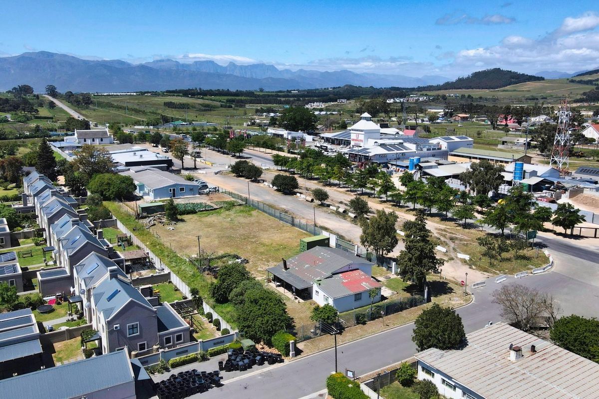 Aerial view of a commercial land parcel situated within a developed area, featuring road access and proximity to existing commercial infrastructure and residential zones.