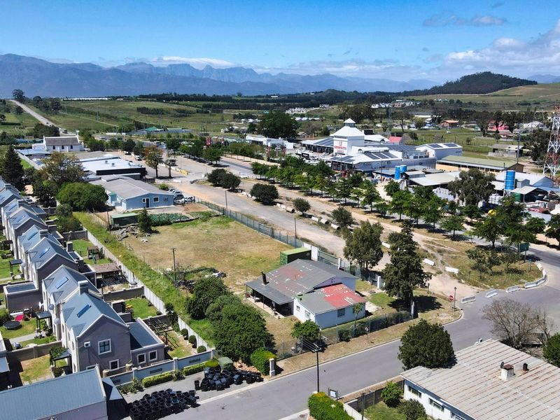 Aerial view of a commercial land parcel situated within a developed area, featuring road access and proximity to existing commercial infrastructure and residential zones.