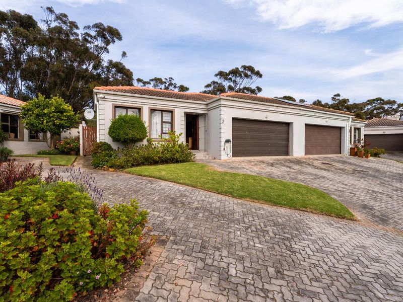 Front elevation of a well-maintained townhouse featuring a double garage, paved driveway, and established garden landscaping.