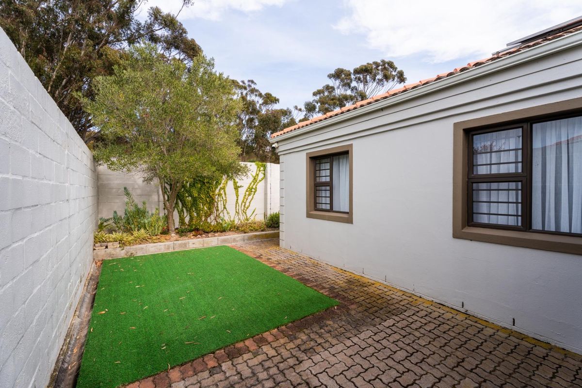 A private rear courtyard featuring paved flooring, an artificial lawn section, and secure boundary walls, providing a low-maintenance outdoor space.