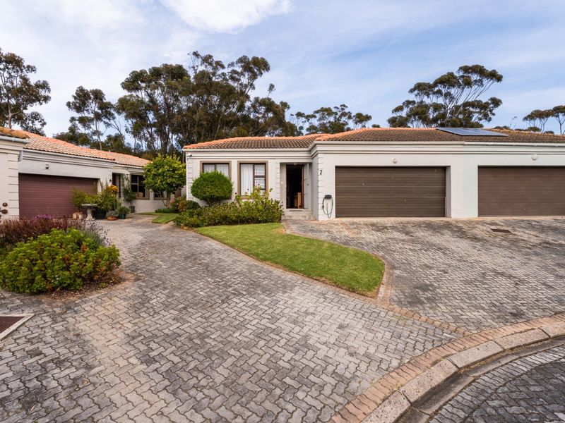 Front exterior view of a townhouse featuring a paved driveway, double garage, and well-maintained garden area.