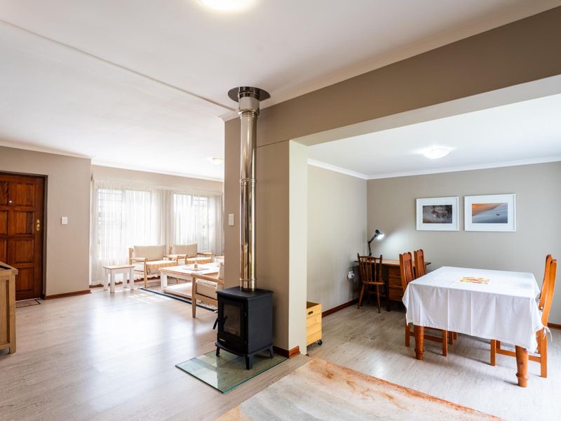 Spacious open-plan living and dining area featuring light laminate flooring and a central freestanding fireplace, creating a warm and inviting atmosphere.