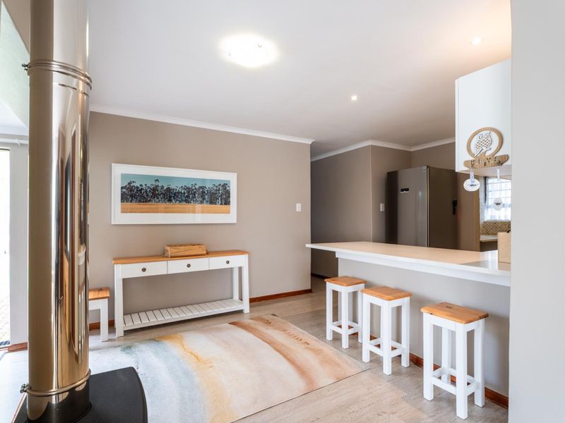 Open-plan living area featuring a modern freestanding fireplace, breakfast bar, and neutral finishes, creating a bright and functional space.