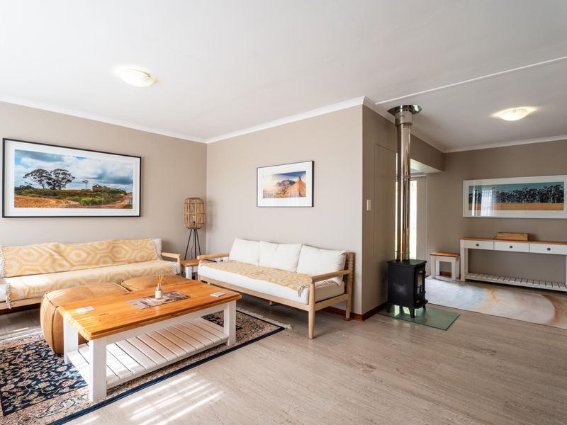 A bright and inviting living room featuring light laminate flooring and a modern wood-burning fireplace, creating a cozy and functional living space.