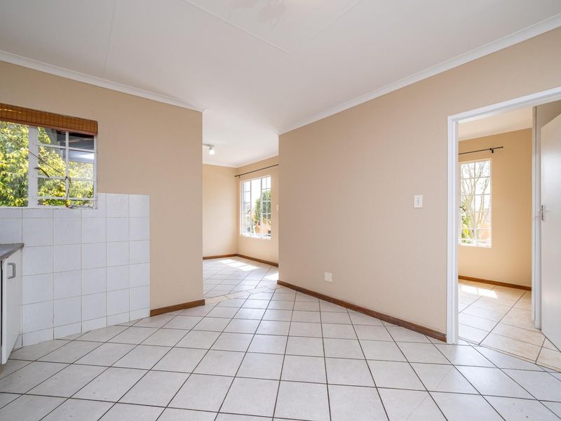 An open-plan living and kitchen area featuring neutral tiled flooring, clean wall finishes, and natural light, providing a versatile blank canvas for interior design.