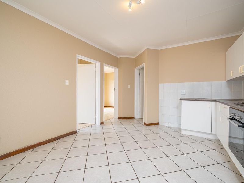 An empty kitchen featuring white built-in cabinetry, a tiled splashback, laminate countertops, and a built-in oven with ceramic floor tiles.