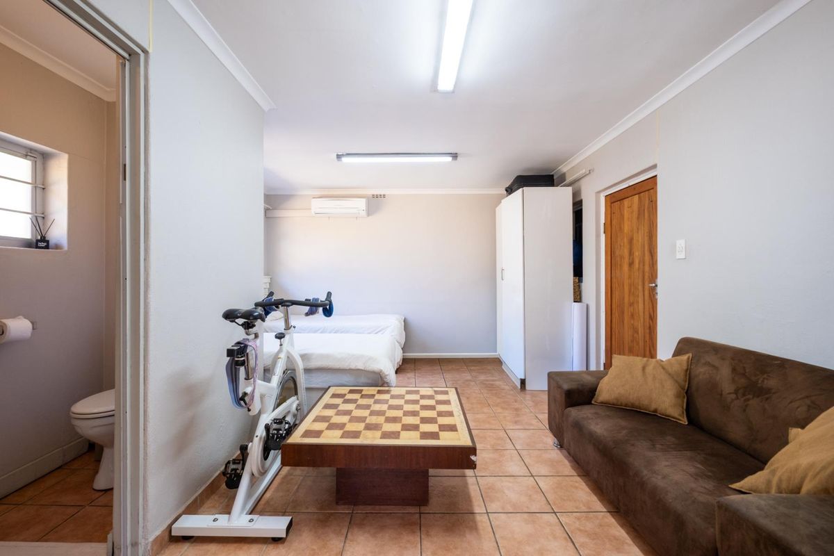 A multi-functional bedroom space featuring tiled flooring, built-in storage, and an integrated air conditioning unit, with an adjacent en-suite bathroom.