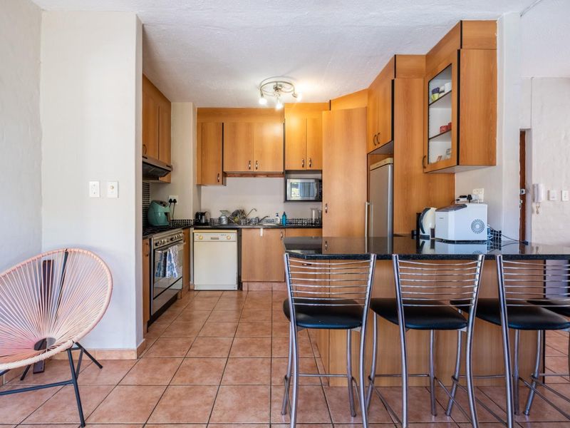 A functional kitchen featuring wood-finish cabinetry, granite countertops, a breakfast bar, and tiled flooring, providing a practical layout for daily cooking and dining.