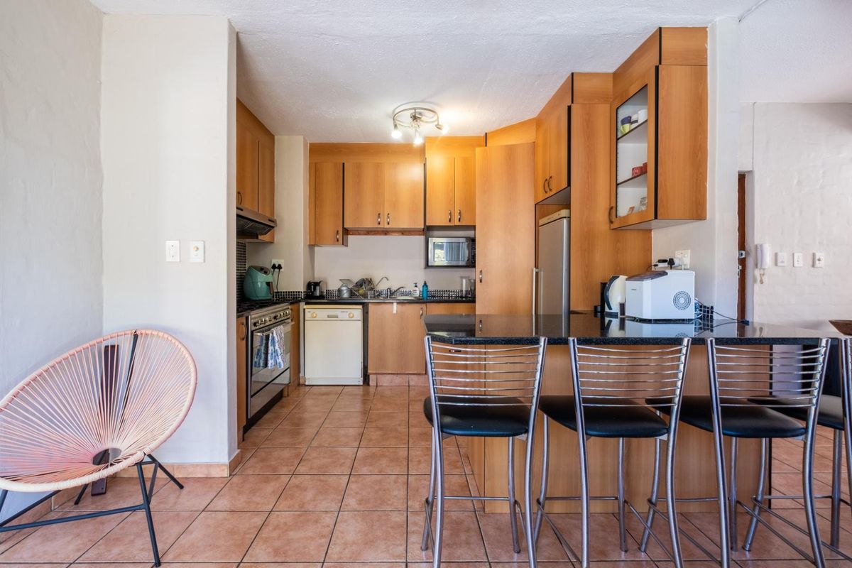 A functional kitchen featuring wood-finish cabinetry, granite countertops, a breakfast bar, and tiled flooring, providing a practical layout for daily cooking and dining.