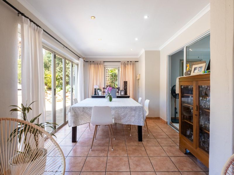 A bright dining room featuring tiled flooring, recessed downlighting, and large sliding glass doors that provide direct access to the outdoor area.