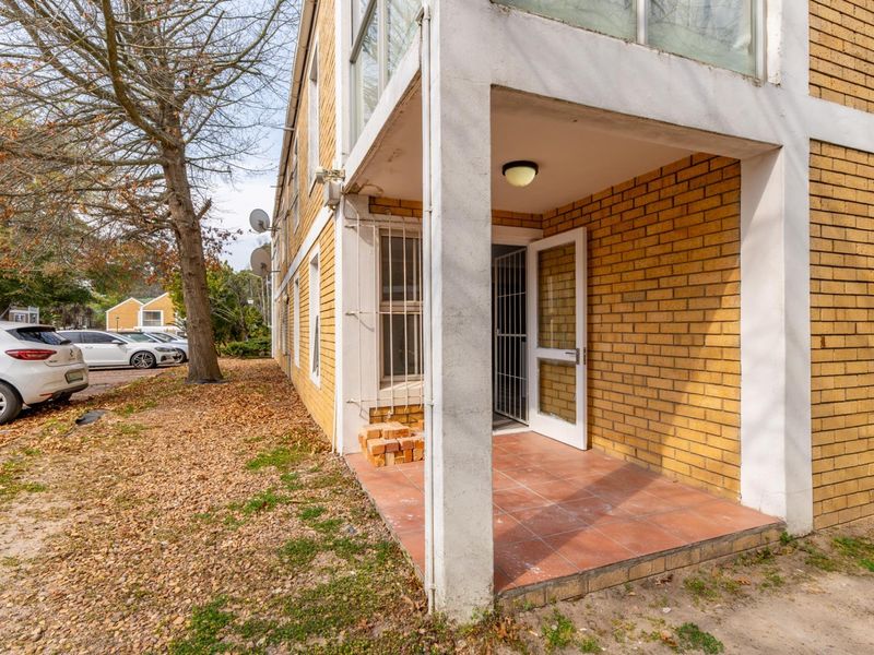 A ground floor patio area featuring tiled flooring and direct access to the apartment, showing signs of wear and requiring maintenance.