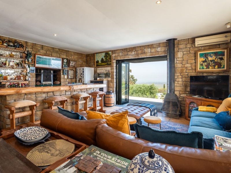 Rustic entertainment area featuring stone-clad walls, a built-in bar, a freestanding fireplace, and large stacking doors opening to an outdoor view.
