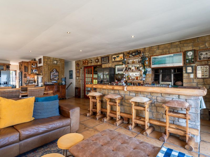 Spacious open-plan living area featuring a rustic stone-clad built-in bar with integrated shelving and recessed lighting.