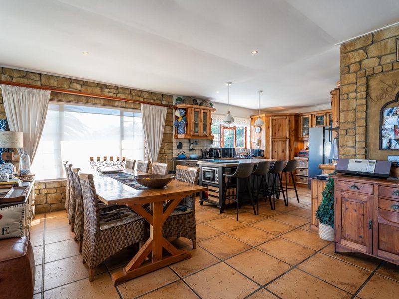 Spacious open-plan kitchen and dining area featuring rustic stone wall accents, tiled flooring, and a central kitchen island with breakfast bar seating.