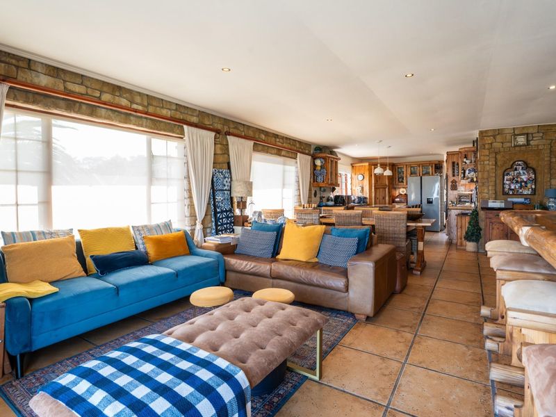 Spacious open-plan living and kitchen area featuring rustic stone walls, tiled flooring, and a large breakfast bar, creating a warm and inviting atmosphere.