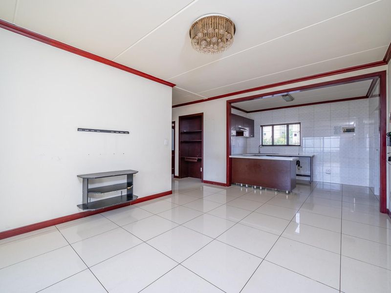 Spacious open-plan living area featuring tiled floors and a functional kitchen with built-in cabinetry, offering a blank canvas for modern updates.