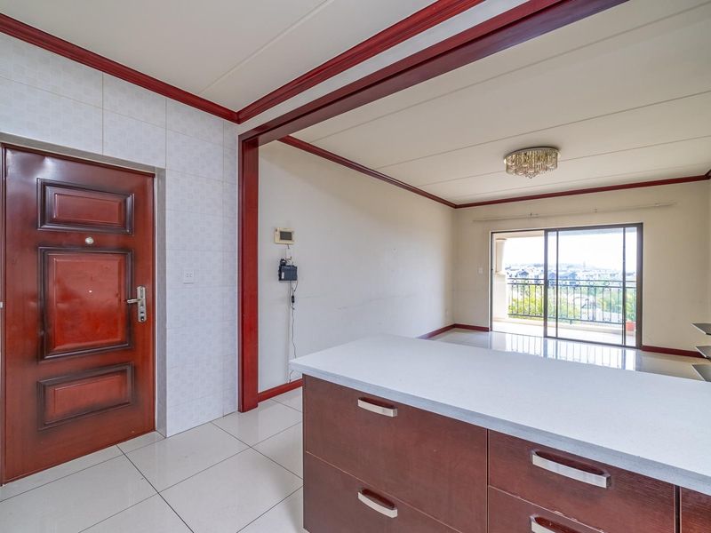 Open plan living area featuring a kitchen island, tiled flooring, and a sliding glass door leading to a balcony with scenic views.