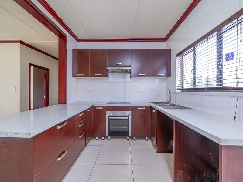A functional kitchen featuring dark wood cabinetry, built-in oven and hob, tiled backsplash, and ample counter space, ready for a modern update.