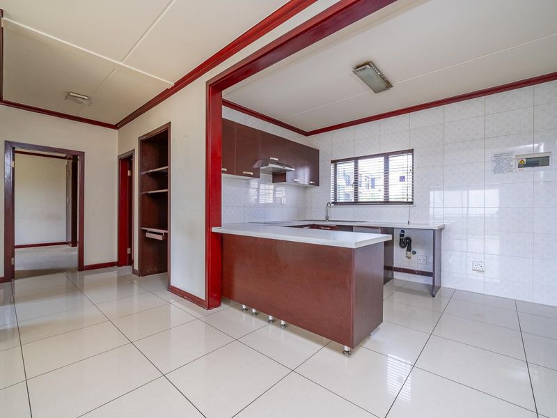 A functional kitchen featuring built-in cabinetry, tiled backsplash, and a breakfast counter, offering a clean, blank canvas for potential modern updates.