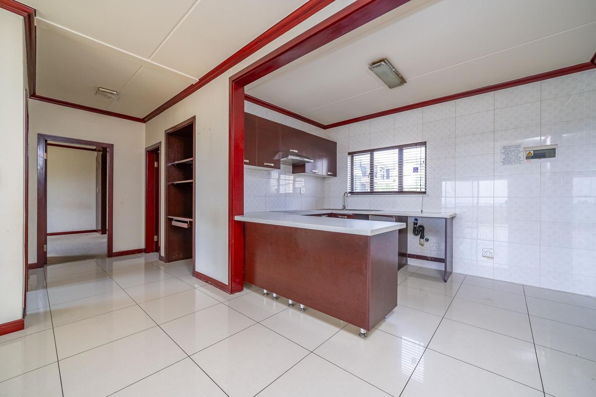 A functional kitchen featuring built-in cabinetry, tiled backsplash, and a breakfast counter, offering a clean, blank canvas for potential modern updates.